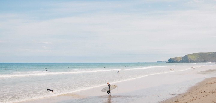 Man with surfboard going into sea. Beach Retreats.